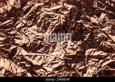 futuristic metallic background, bronze brown crumpled foil. Stock Photo