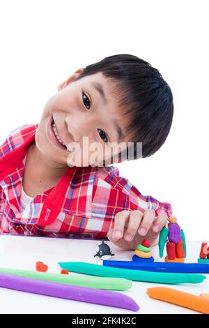 Smart asian boy playing and creating toys from play dough. Child smiling and show his works from clay, on white background. Strengthen the imagination Stock Photo