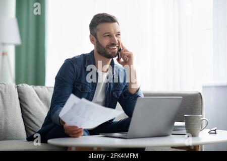 Happy businessman working with documents, talking to clients on smartphone Stock Photo