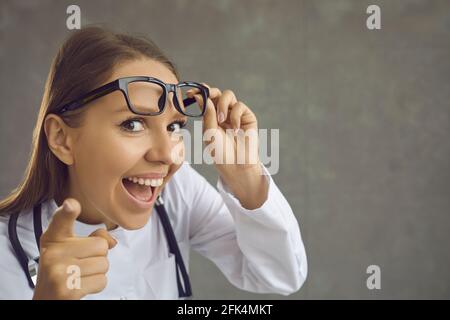 Funny female doctor smiling with open mouth pointing to camera with finger Stock Photo
