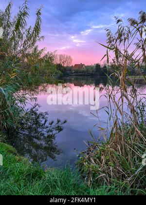 House at the lake with a dramatic sunset sky and a beautiful reflection on the lake. Stock Photo