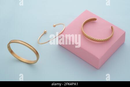 Three modern Golden bracelets collection on pink and blue background Stock Photo
