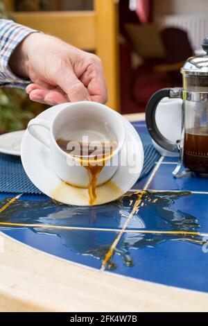 Cup of coffee spilling on a table Stock Photo