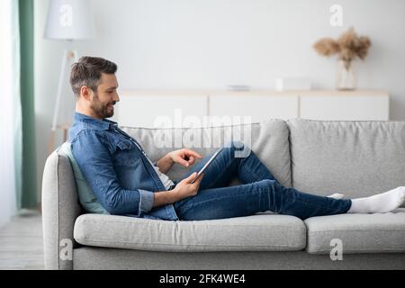 Relaxed bearded man using digital tablet at home Stock Photo
