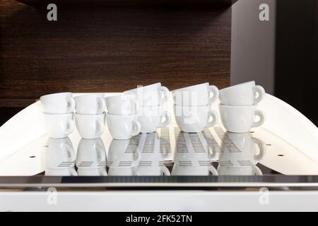 Clean white coffee cups for espresso and cappuccino stand on top of the coffee machine. Copyspace. Shallow focus. Stock Photo