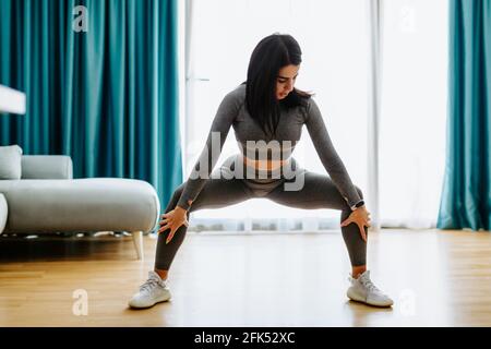 Young attractive woman practicing yoga at home. Legs stretching practice Stock Photo