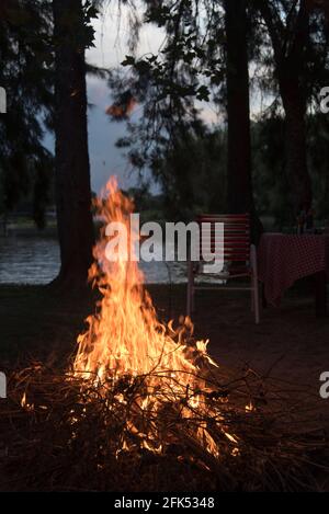 Bonfire on the bank of a river. Concepts of traveling, being in nature, outdoor fun. Vertical image without people with copy space. Stock Photo