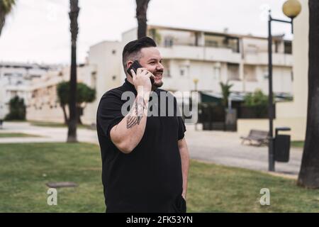 Cheerful Caucasian male talking on the phone and walking on a street Stock Photo