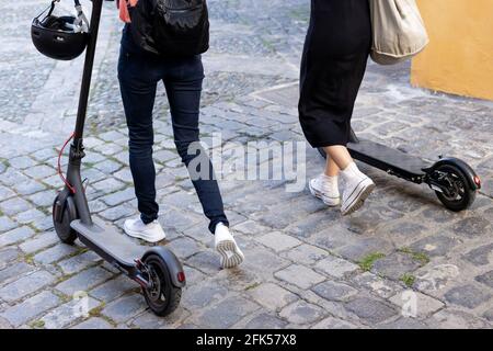 Unrecognisable women riding around on electric scooters Stock Photo