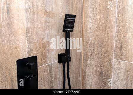 https://l450v.alamy.com/450v/2fk5a9p/black-matte-hand-shower-mounted-on-a-tiled-wall-imitating-wood-2fk5a9p.jpg