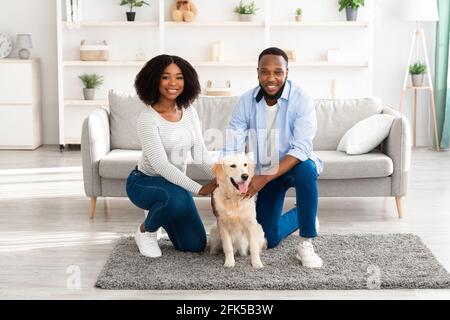 Young black couple hugging with dog posing at home Stock Photo