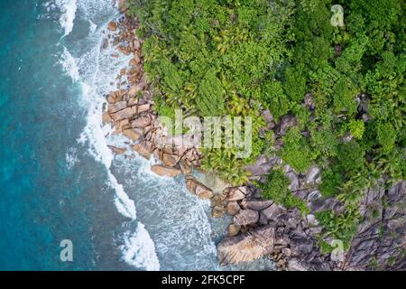 Drone field of view of waves crashing into cliffs along coastline Praslin, Seychelles. Stock Photo