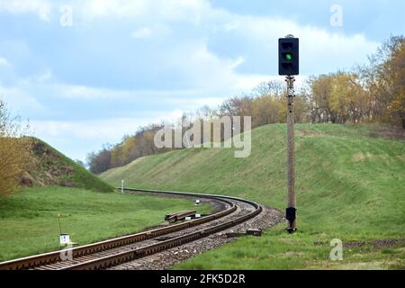 Selective focus railway green lantern of semaphore railroad enable, allow permit track that twists and turns between hills. Empty rounding and turning Stock Photo