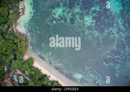 Drone field of view of fishing boats and pristine coastline and forest Praslin, Seychelles. Stock Photo