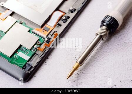 Bad electrical circuit being repaired by a technician with a tin soldering iron. Stock Photo