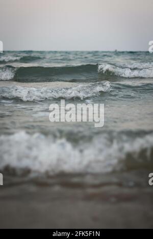 Vertical shot of beautiful foam waves washing the shore Stock Photo