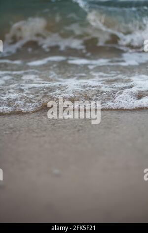 Vertical shot of beautiful foam waves washing the shore Stock Photo