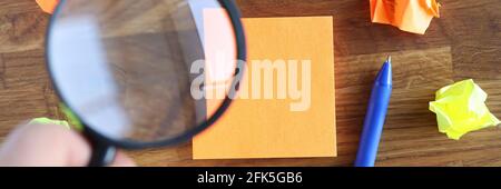 Hand holding magnifying glass over sticker closeup Stock Photo
