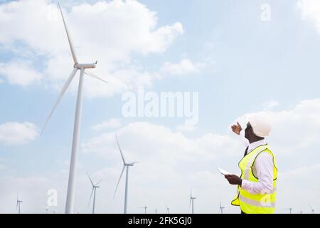 African engineer windmills working on tablet with the wind turbine in background Stock Photo