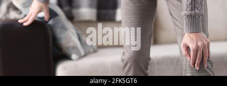 Man getting up from couch and holding on to sore knee closeup Stock Photo