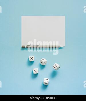 Yahtzee game in progress. Rolling dice, pencil and score sheet on a blue background. Abstract concept with copy space. Flat lay. Stock Photo