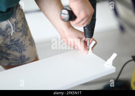 Close-up of male foreman making hole in wooden plank with drill Stock Photo