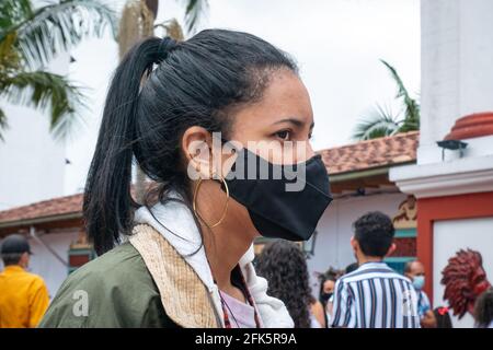 Guatapé, Antioquia, Colombia - April 4 2021: Young Latina Woman Wearing a Black Mask is Standing front the Church Stock Photo