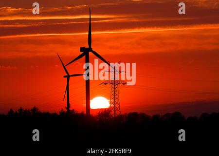 Ockholm, Germany. 28th Apr, 2021. The sun sets behind power line poles and wind turbines. Credit: Frank Molter/dpa/Alamy Live News Stock Photo