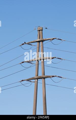 View on a stone high voltage electric transmission pylon against blue sky in Switzerland Stock Photo