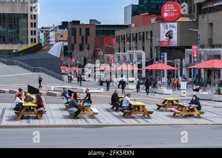 Montreal, CA - 28 April 2021: People sitting at picnic tables on Ste Catherine Street in Montreal Downtown. Stock Photo