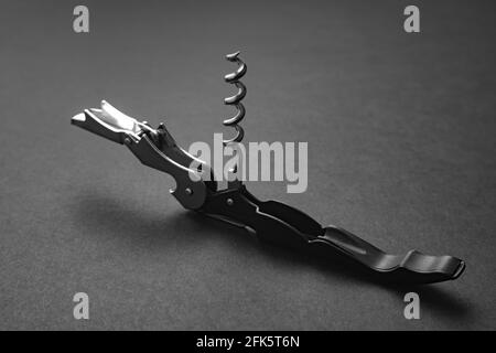 Opened sommelier knife with corkscrew and bottle opener, professional waiter knife, on black background. Stock Photo