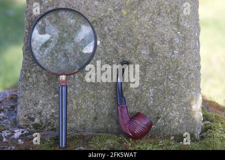 magnifying glass and pipe on the grave of Sir Arthur Conan Doyle in All Saints Churchyard, Minstead, New Forest District, Hampshire, England Stock Photo