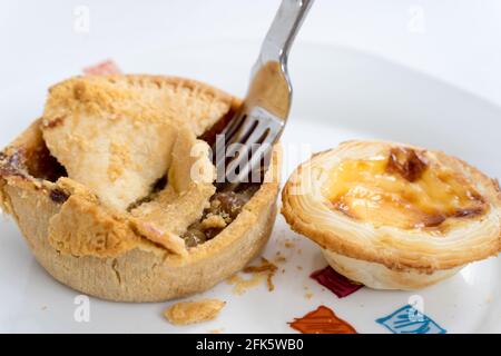 fork tuck into Chicken pie with egg tart as side dish Stock Photo