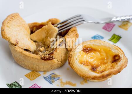 a Fork tuck into Chicken pie with egg tart as side dish Stock Photo