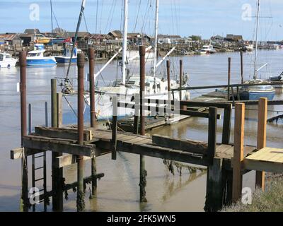 Boats moored at jetties on the Walberswick side of the River Blyth looking across towards the community of Southwold Harbour on the other side. Stock Photo