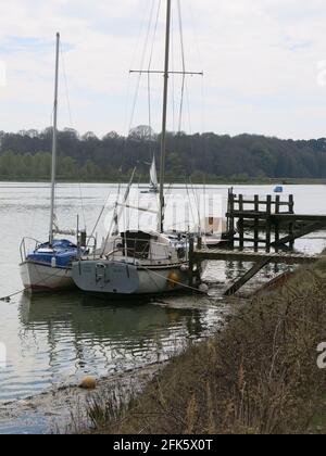 Two yachts moored at a jetty on the banks of the River Deben, by the footpath between Melton and Woodbridge, Suffolk. Stock Photo