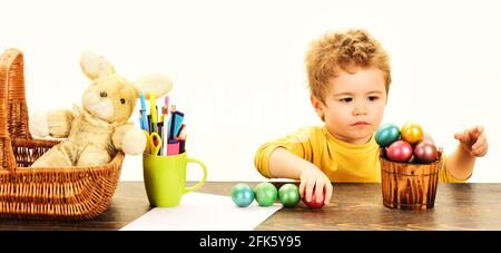 Little child painting Easter Eggs. Childrens Easter creativity. Kid boy decorate Easter egg. Stock Photo