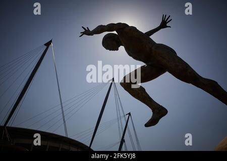Colin Spofforth's bronze sculpture 'THE RUNNER' with Manchester City’s Etihad Stadium behind Stock Photo
