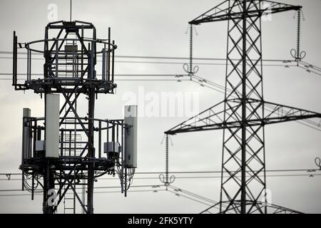 Close up of a silhouetted Cellular network phone mast and electric lattice tower pylon Stock Photo