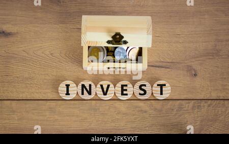 Invest symbol. Concept word invest on wooden cubes on a beautiful wooden background, small wooden chest with coins. Business and invest concept.