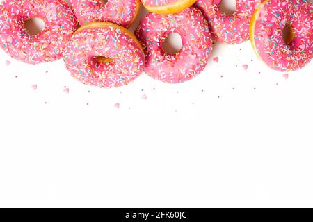 Top donuts border. Top view of yummy fresh homemade doughnuts. Light background for you text. Confetti in shape of little hearts. Valentine border.  Stock Photo
