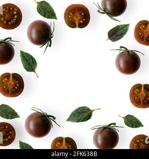 Kumato cherry tomatoes with basil leaves on white background. Stock Photo