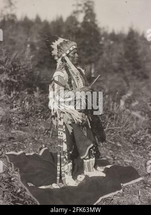 White Bird - Photograph shows White Bird, an American Indian man of the Plateau region, full-length portrait, standing, facing left, wearing feather headdress - Frank Woodfield, 1911 Stock Photo