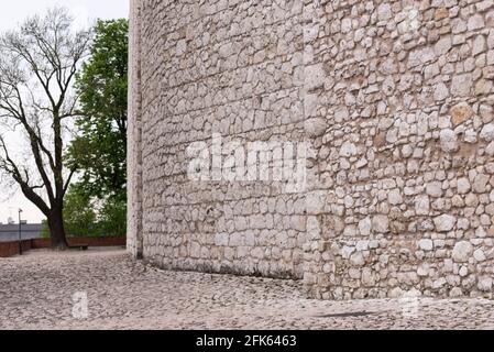 White stone wall. The wall of one of the castles in the center of Krakow. Stone pavement turning into a wall, made of one material. Stock Photo