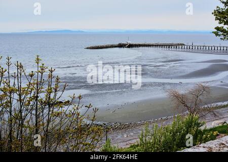 White Rock beach and pier at low tide.  On the horizon, sit BC's Gulf Islands.  Spring 2021 Stock Photo