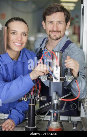 portrait of engineer and apprentice examining component in factory Stock Photo