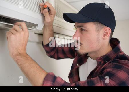 a male technician cleaning air conditioner indoors Stock Photo