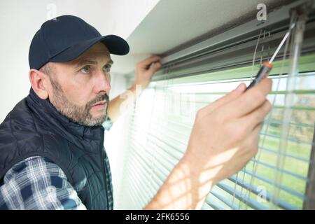 male contractor installing window blinds Stock Photo