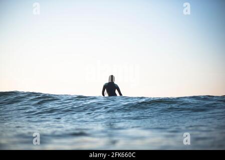 Individual Asian Woman in summer surf lineup at dawn Stock Photo