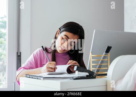 Focused teen studying at desktop in personal room Stock Photo